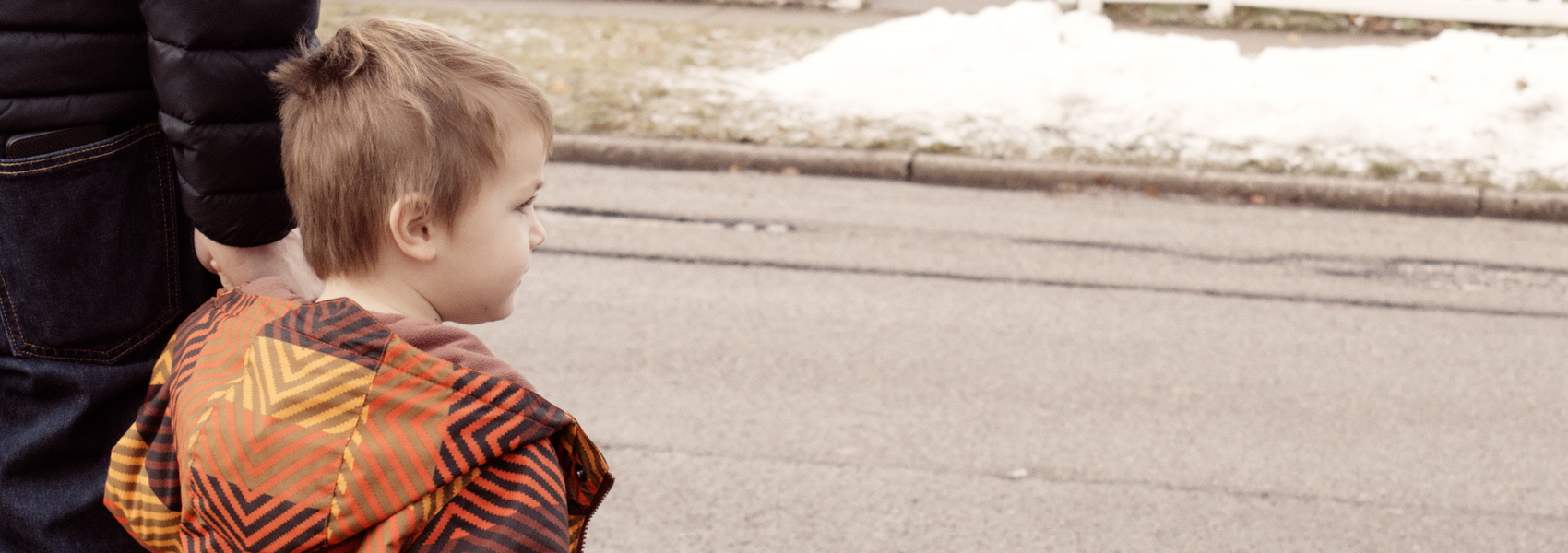 A father holds his young son's hand to cross the street